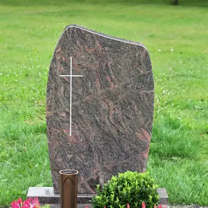 Steingrabstein mit Kreuzsymbol auf einem Friedhof, mit Blumen und Dekorationen im Vordergrund.