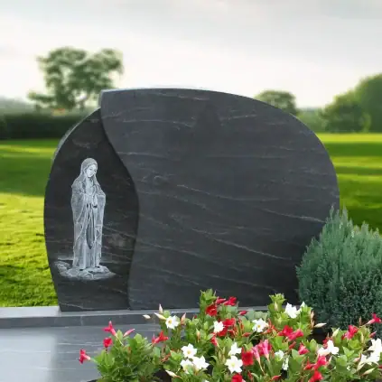 Eleganter Grabstein aus schwarzem Granit mit detaillierter Christus-Relief im Friedhofsland, umgeben von bunten Blumen und grünen Pflanzen, ideal für individuelle Gedenkstätten und Trauerrituale.