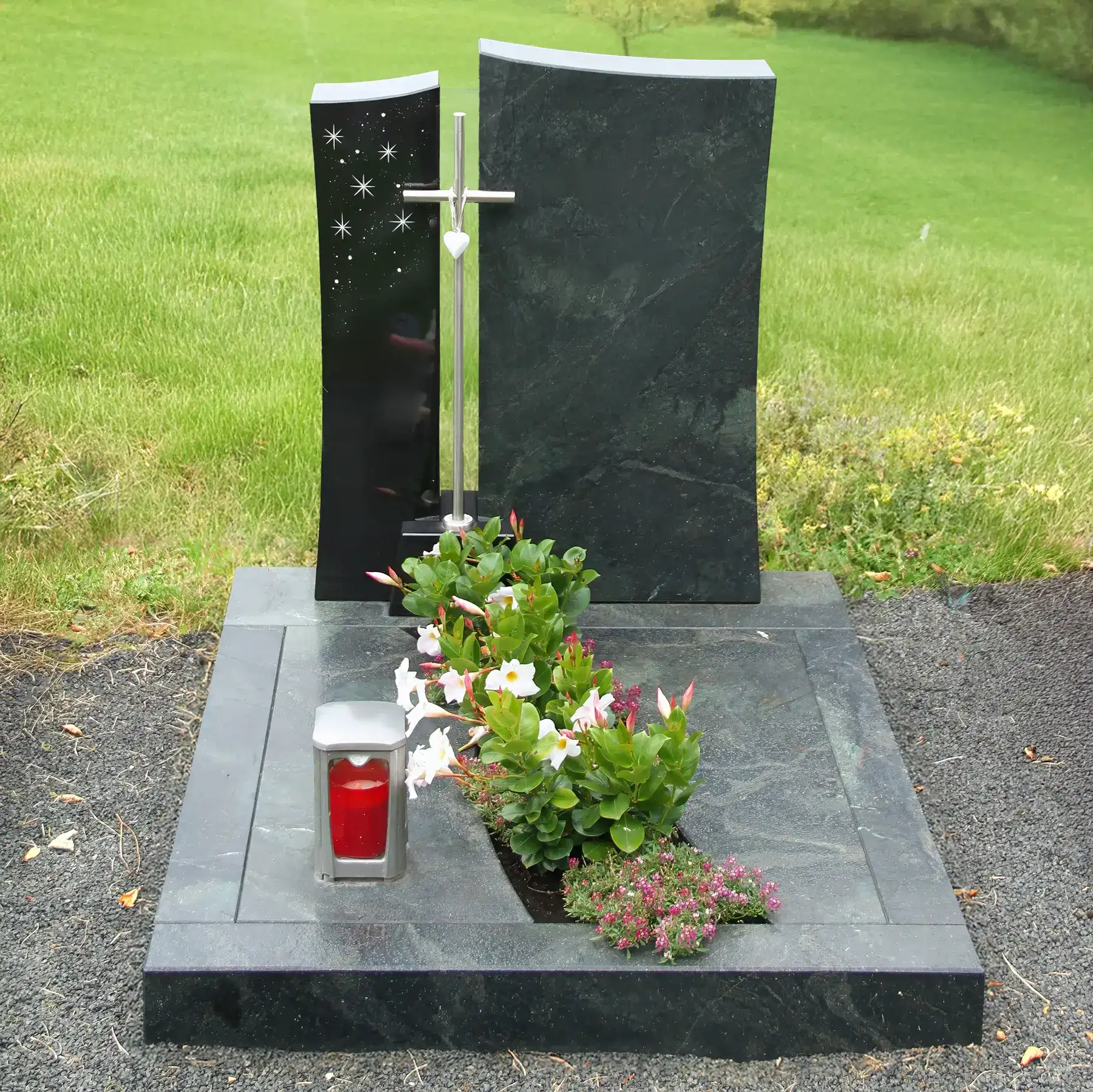 Zweiteiliger Urnengrabstein aus Indian Black und Alexandria mit Edelstahlkreuz, Swarovski-Sternen, Blumen und Kerze, ideal für würdevolle Grabgestaltung.